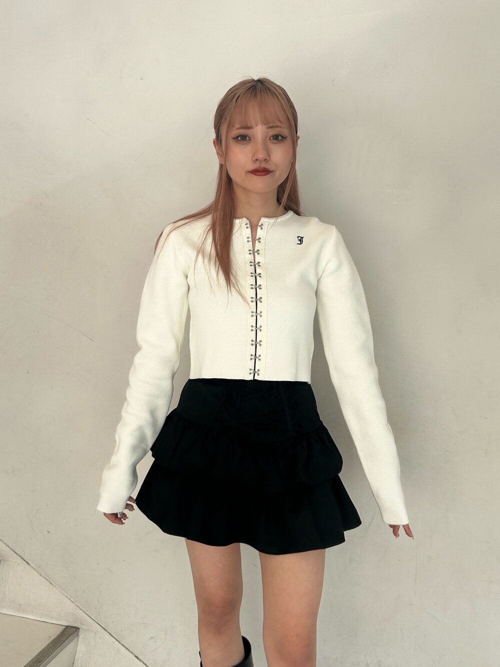 ホワイト系のカーディガン/ボレロ、ブラック系のスカート、ブラック系のブーツを着用したレディースの春コーディネートの4枚目の写真