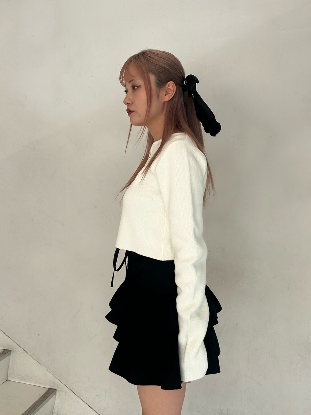 ホワイト系のカーディガン/ボレロ、ブラック系のスカート、ブラック系のブーツを着用したレディースの春コーディネートの5枚目の写真