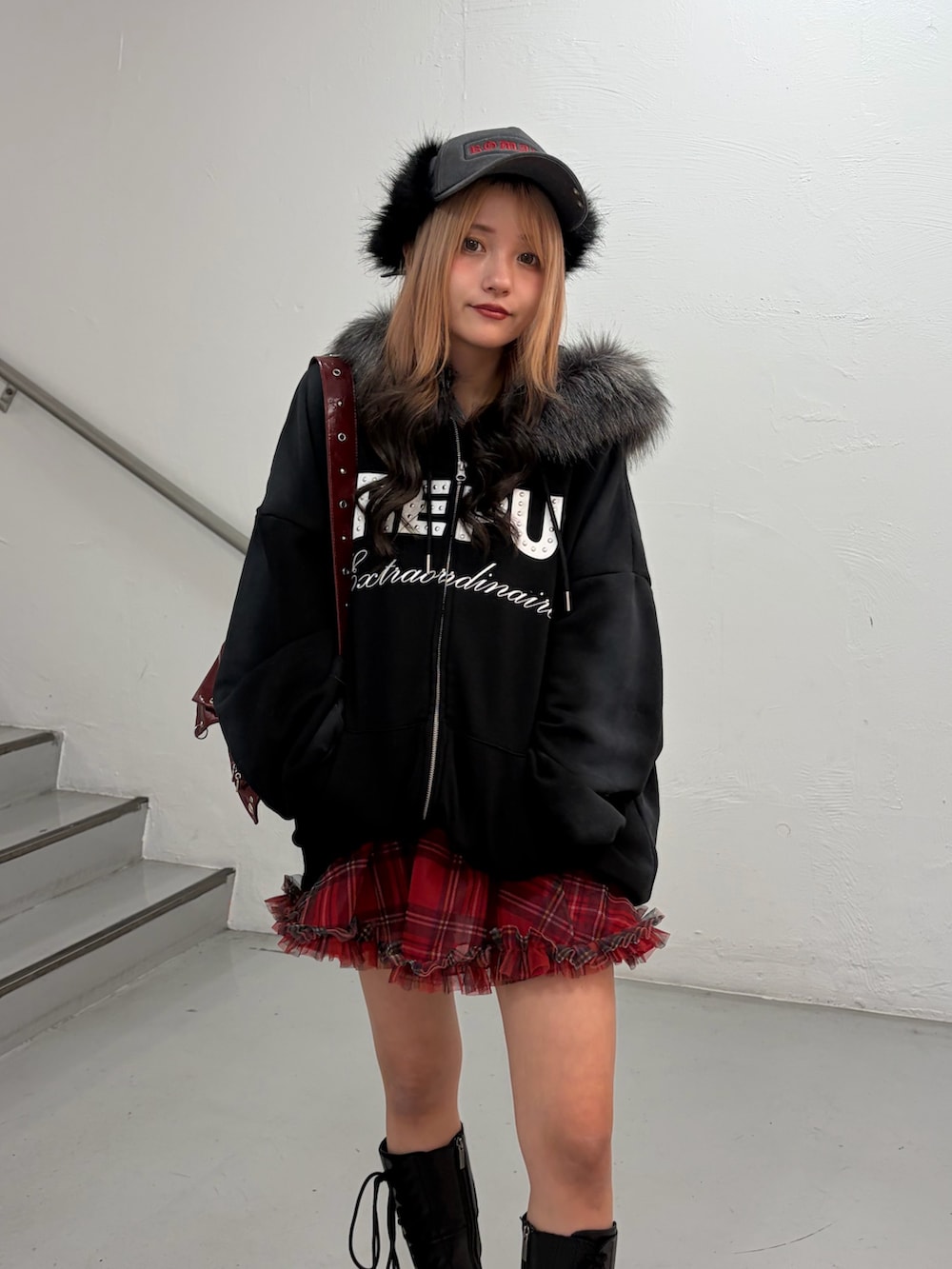 ブラック系のパーカー、レッド系のスカート、レッド系のショルダーバッグを着用したレディースの冬コーディネートの4枚目の写真