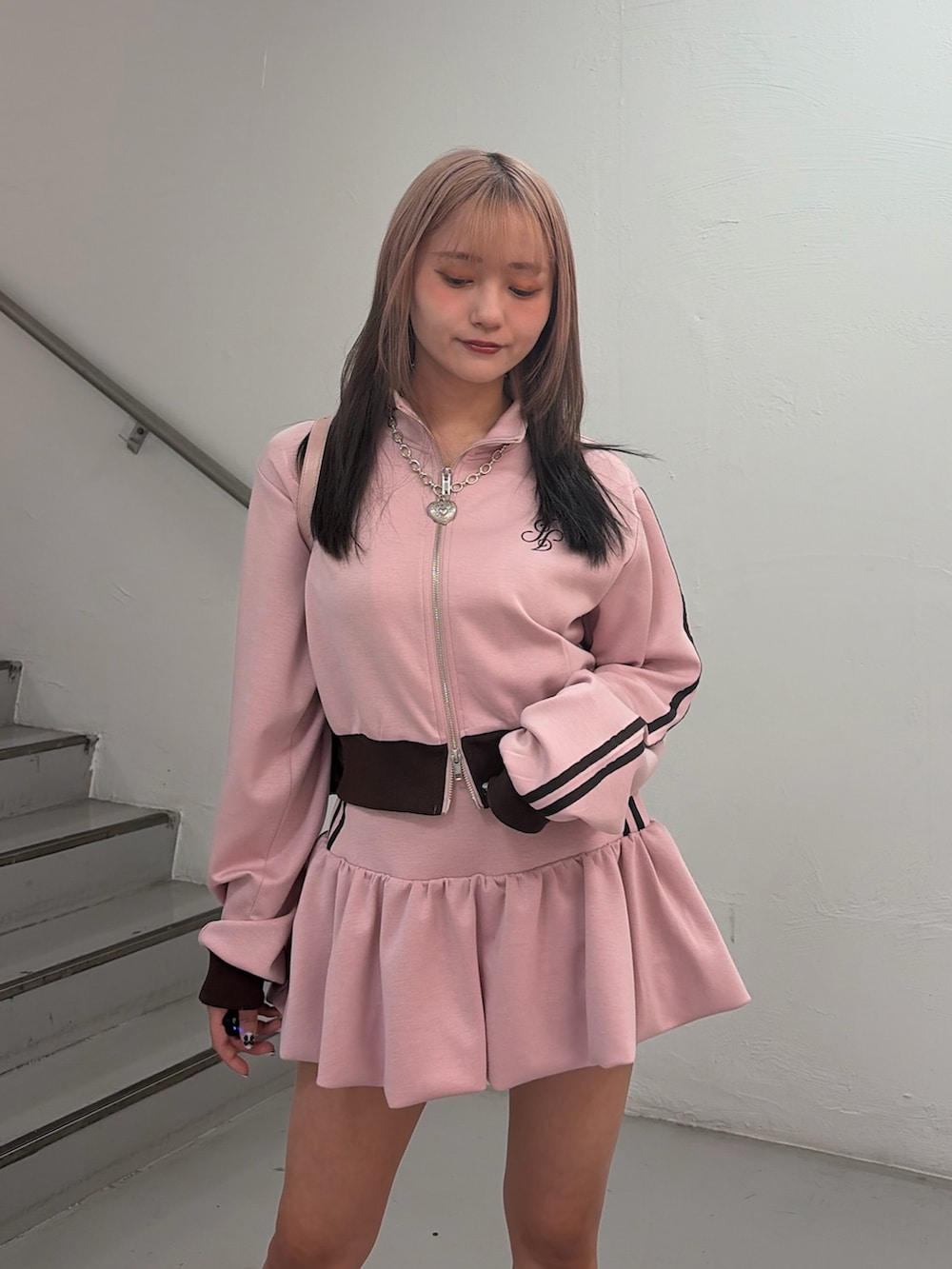 ピンク系のジャージ、ピンク系のスカート、ブラック系のハンドバッグを着用したレディースの冬コーディネートの6枚目の写真