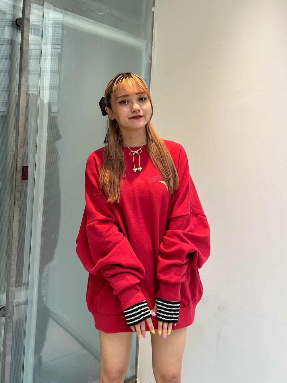レッド系のTシャツ/カットソー、ブラック系のブーツ、ブラック系のアームカバーを着用したレディースの秋コーディネートの5枚目の写真