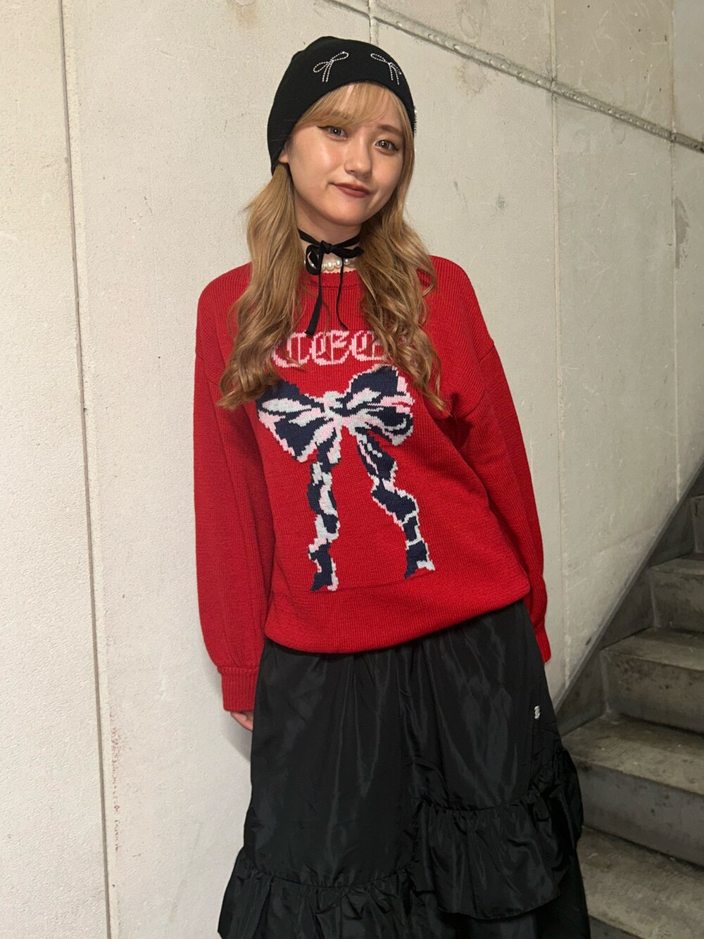 レッド系のニット/セーター、ブラック系のスカート、ブラック系のチョーカーを着用したレディースの秋コーディネートの4枚目の写真