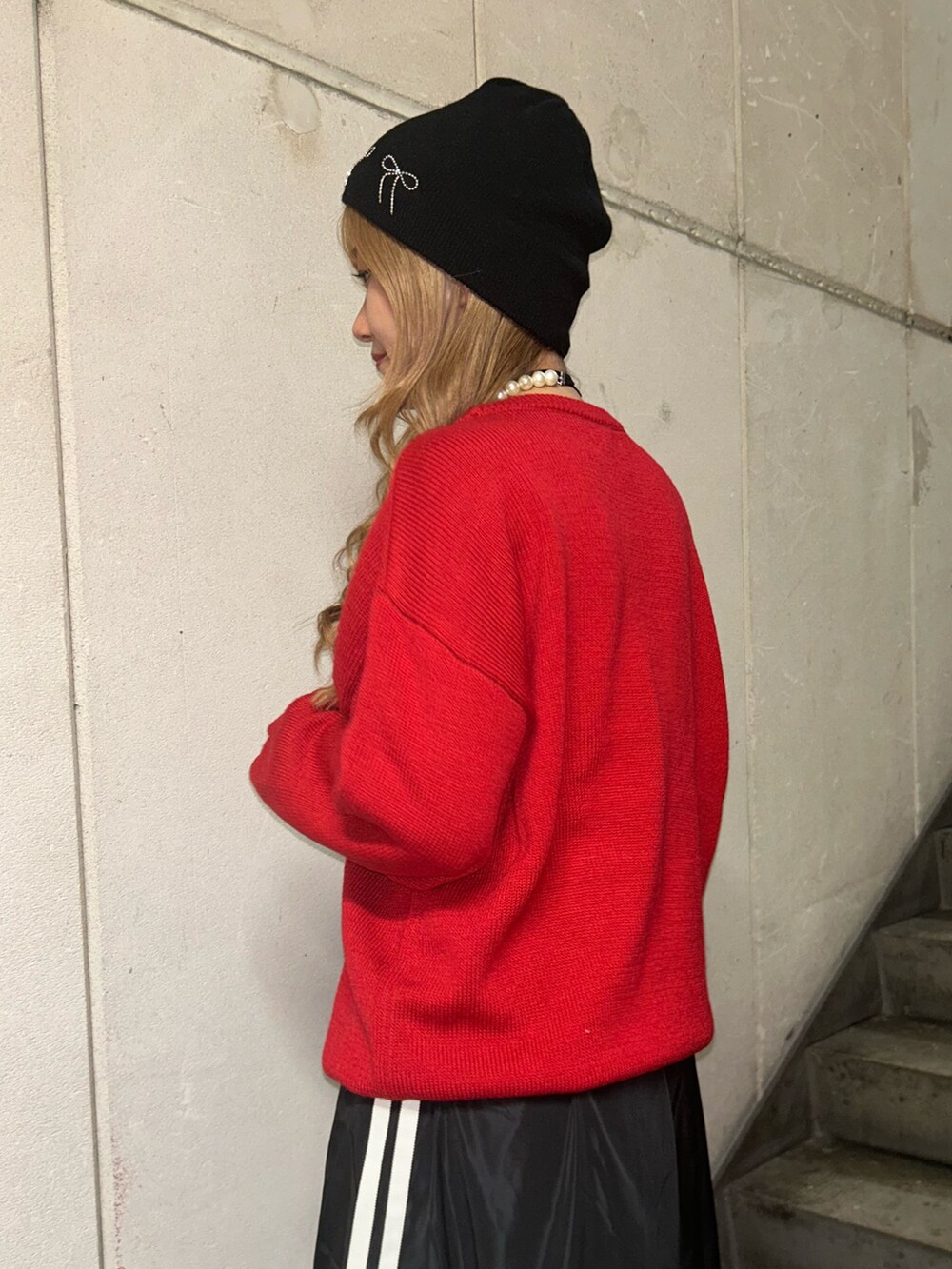 レッド系のニット/セーター、ブラック系のスカート、ブラック系のチョーカーを着用したレディースの秋コーディネートの5枚目の写真