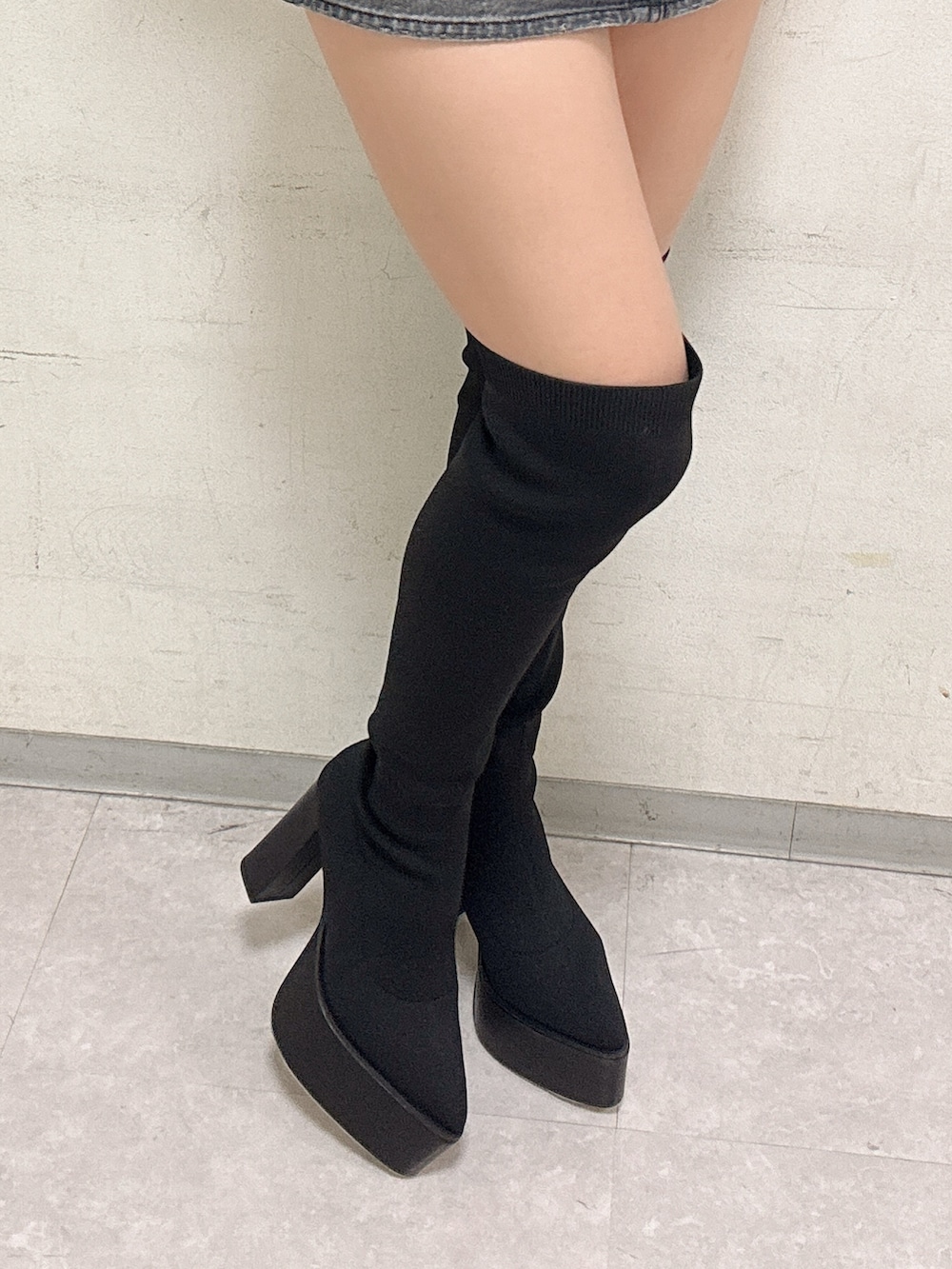 ブラック系のニット/セーター、ブラック系のデニムスカート、ブラック系のブーツを着用したレディースの冬コーディネートの5枚目の写真