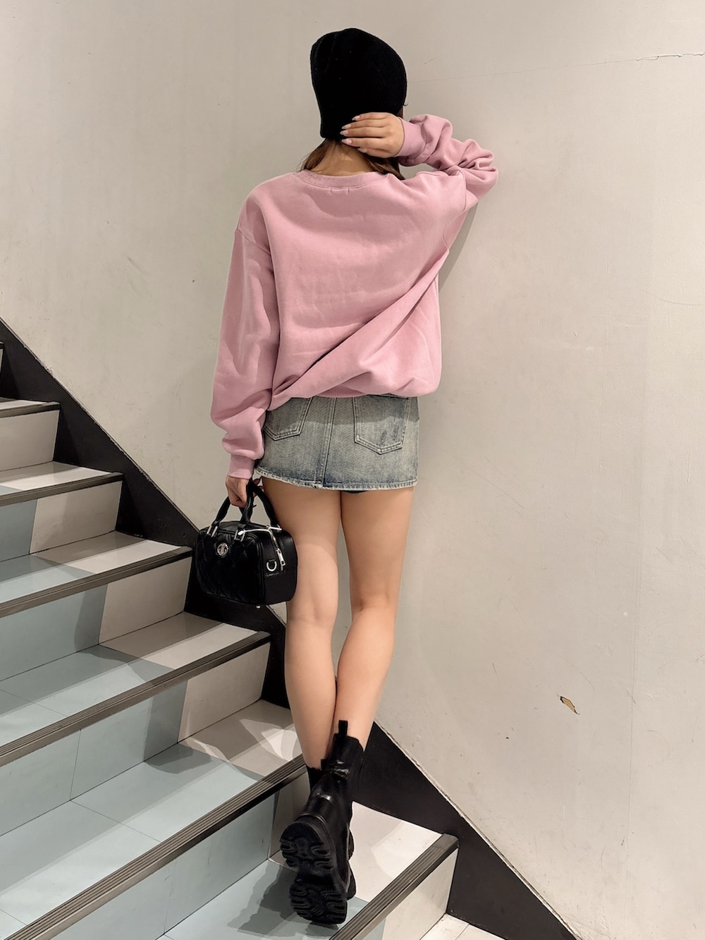 ピンク系のスウェット、ブラック系のハンドバッグ、ブラック系のブーツを着用したレディースの冬コーディネートの3枚目の写真