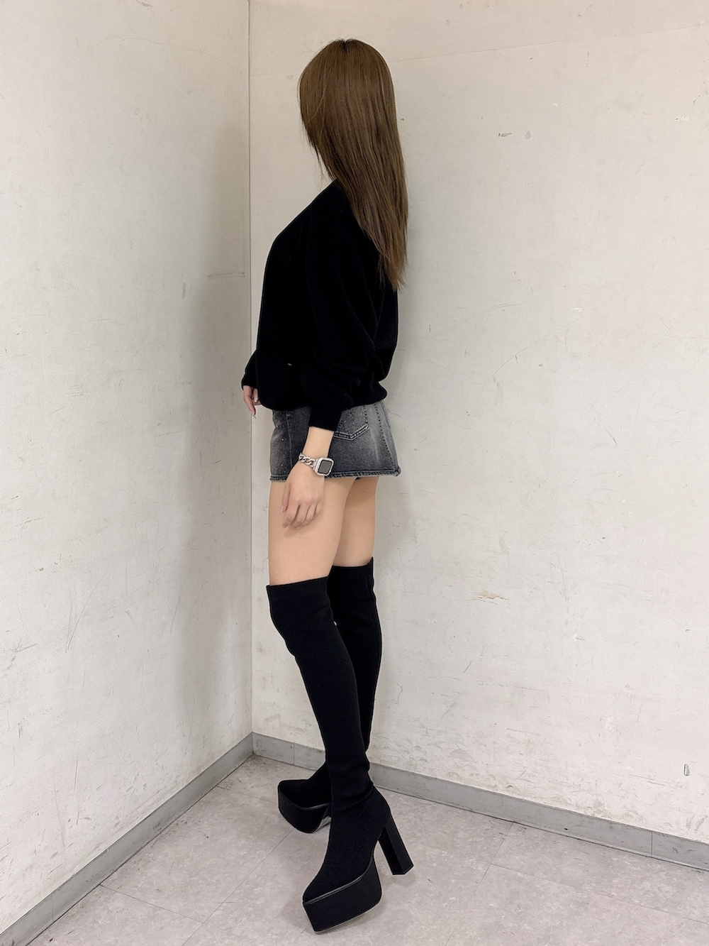 ブラック系のニット/セーター、ブラック系のデニムスカート、ブラック系のブーツを着用したレディースの冬コーディネートの2枚目の写真