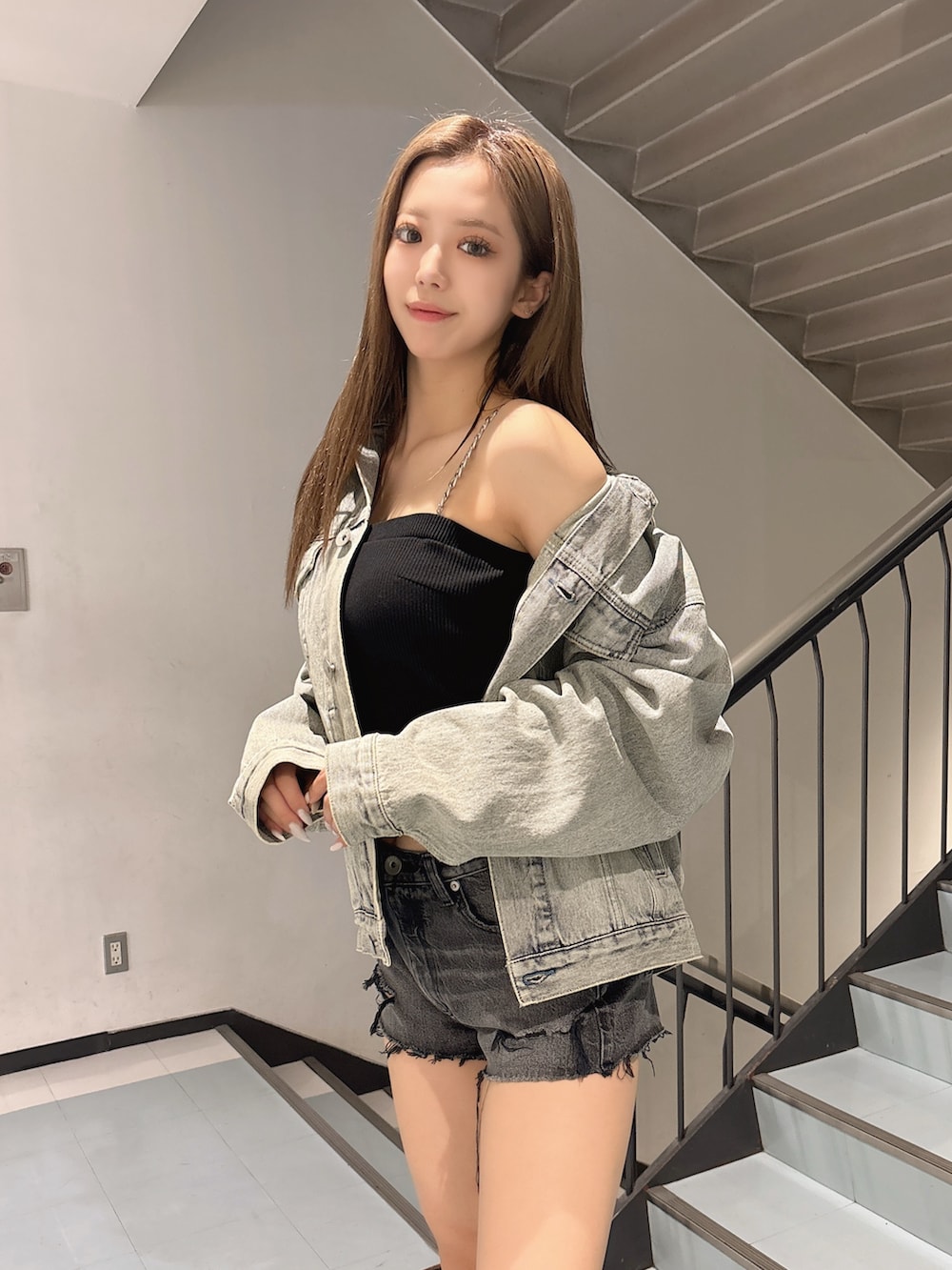 ブルー系のデニムジャケット、ブラック系のデニムパンツ、ブラック系のチューブトップを着用したレディースの春コーディネートの3枚目の写真