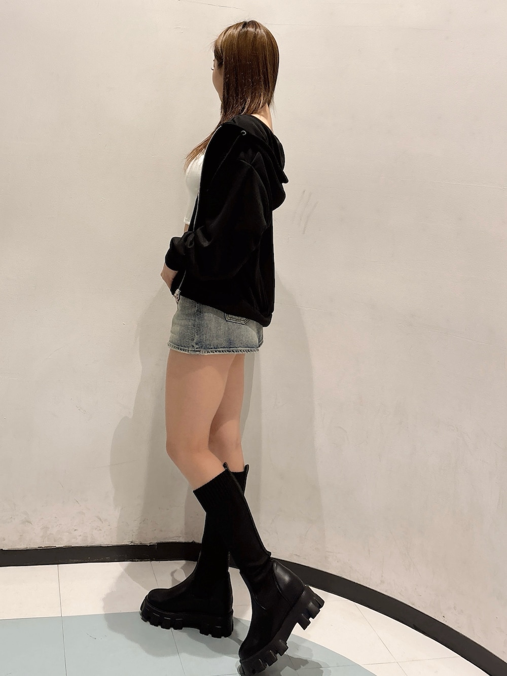 ブルー系のデニムスカート、ブラック系のブーツ、ブラック系のパーカーを着用したレディースの秋コーディネートの2枚目の写真