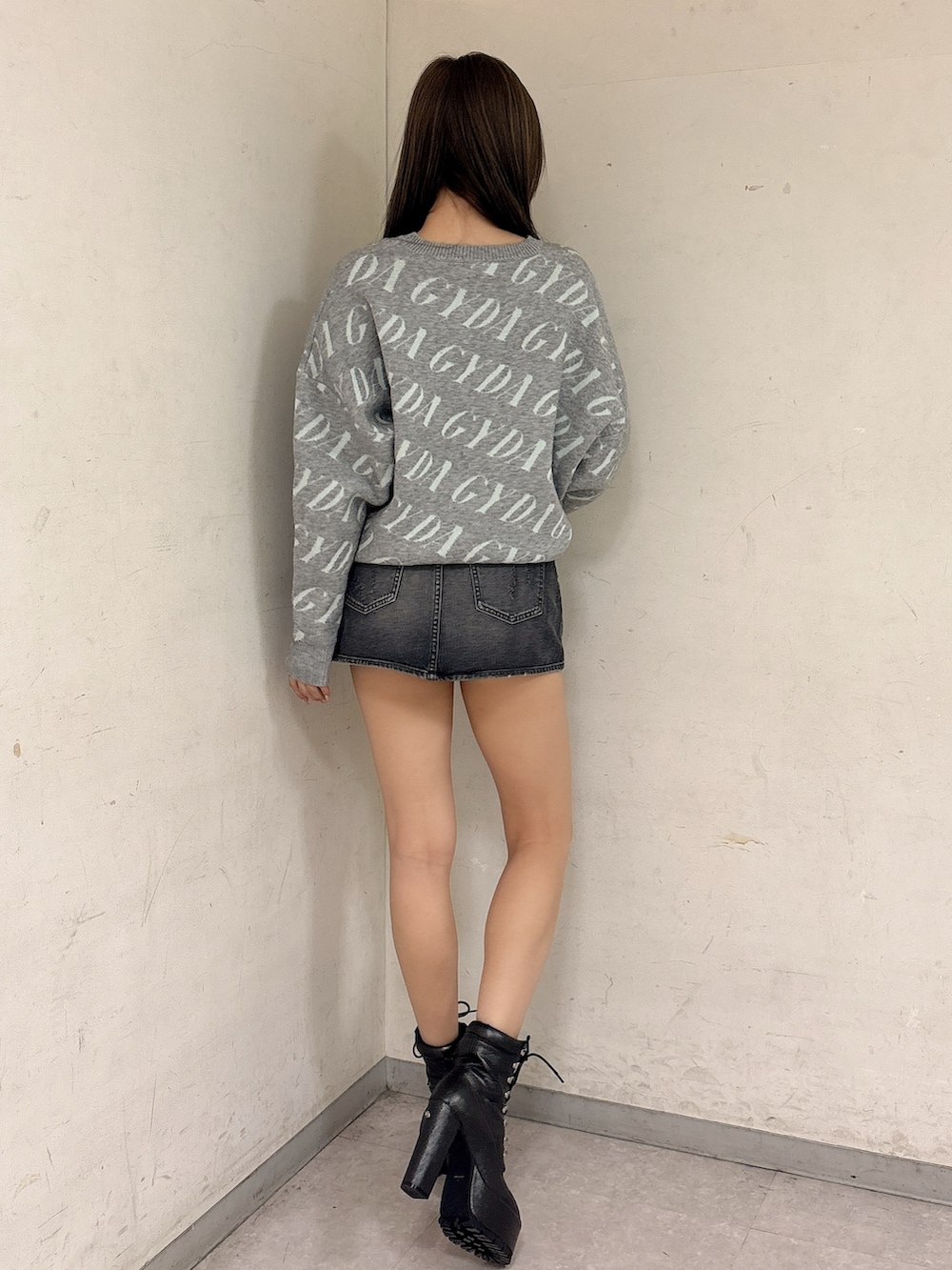 グレー系のニット/セーター、ブラック系のデニムスカート、ブラック系のブーツを着用したレディースの冬コーディネートの3枚目の写真