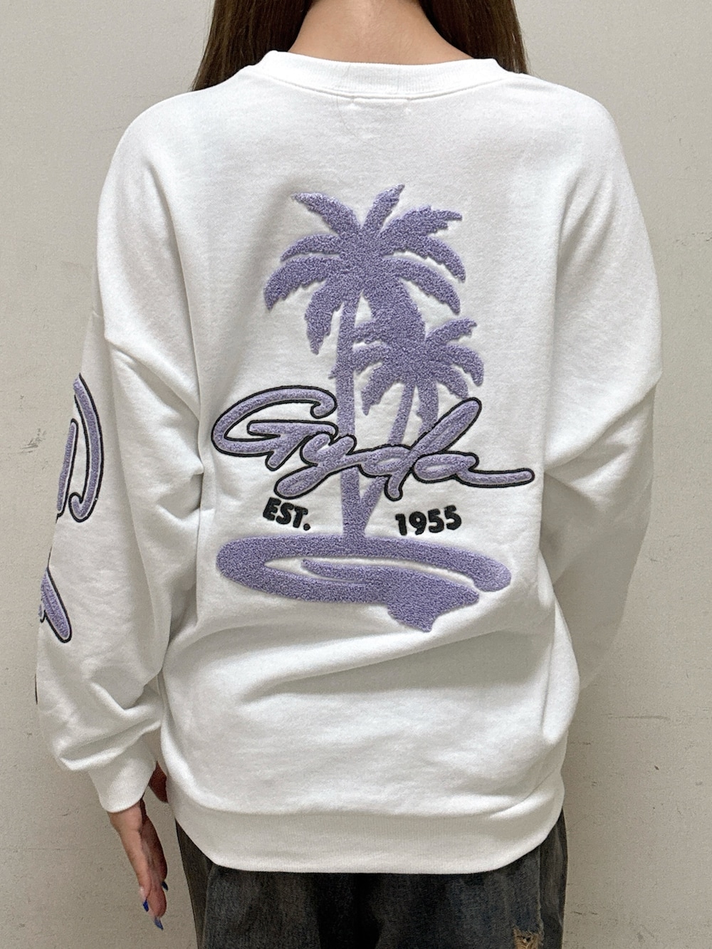 ホワイト系のスウェット、ブルー系のデニムパンツ、ブラック系のパンプスを着用したレディースの秋コーディネートの5枚目の写真