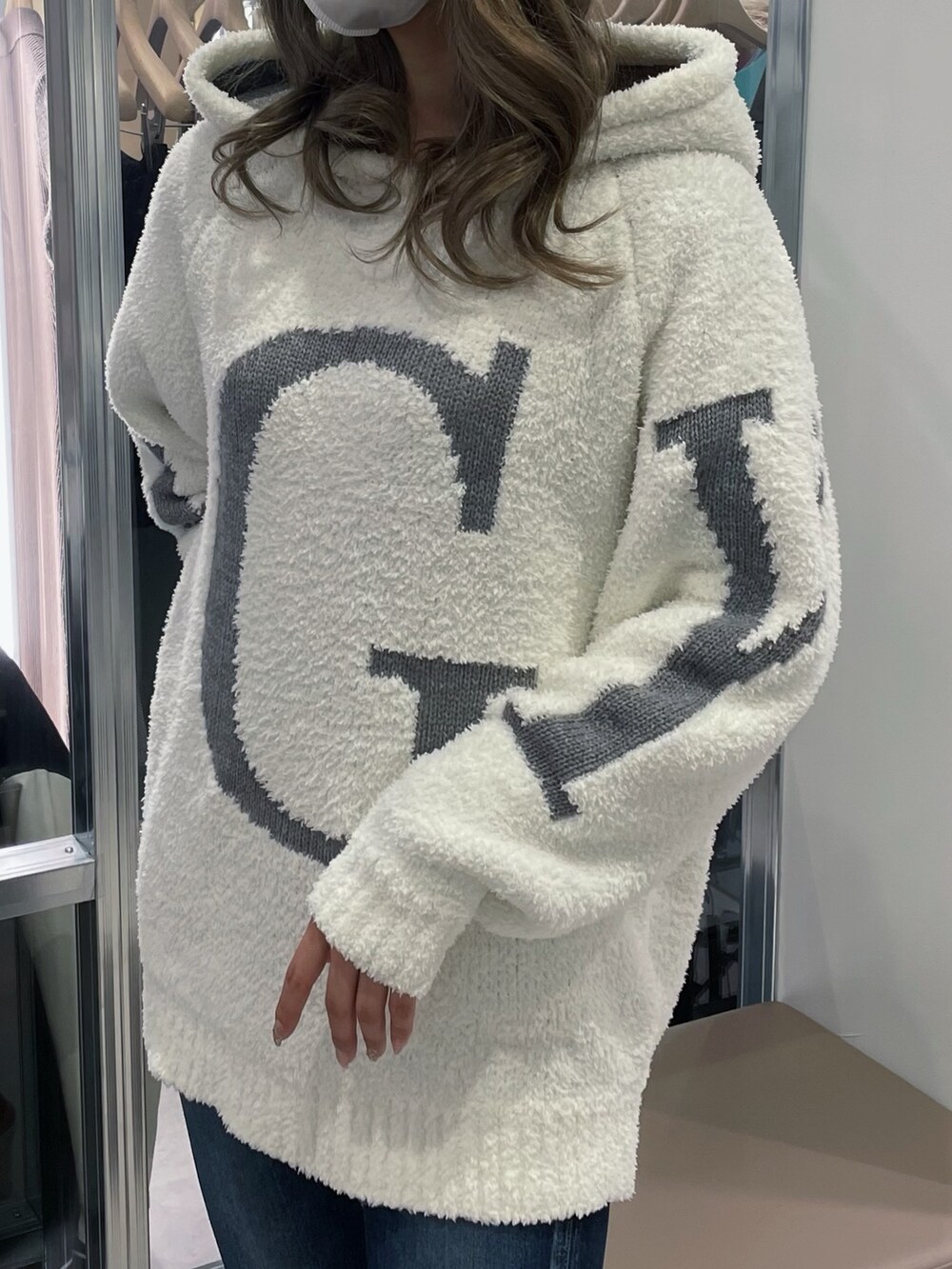 ホワイト系のニット/セーター、ブルー系のデニムパンツ、ホワイト系のパンプスを着用したレディースの冬コーディネートの3枚目の写真