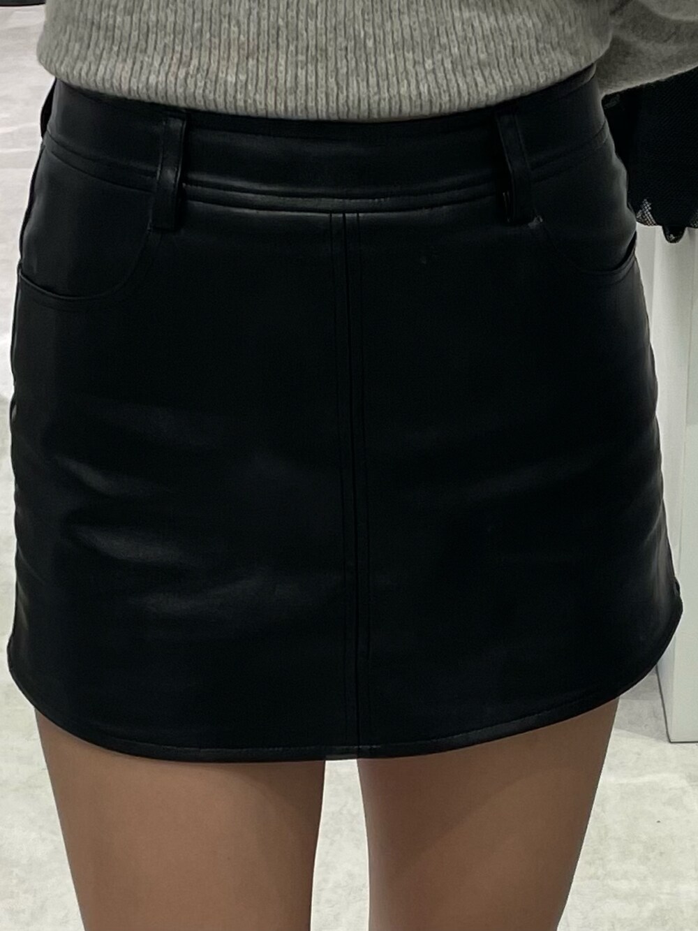 グレー系のニット/セーター、ブラック系のスカート、ブラック系のブーツを着用したレディースの冬コーディネートの3枚目の写真