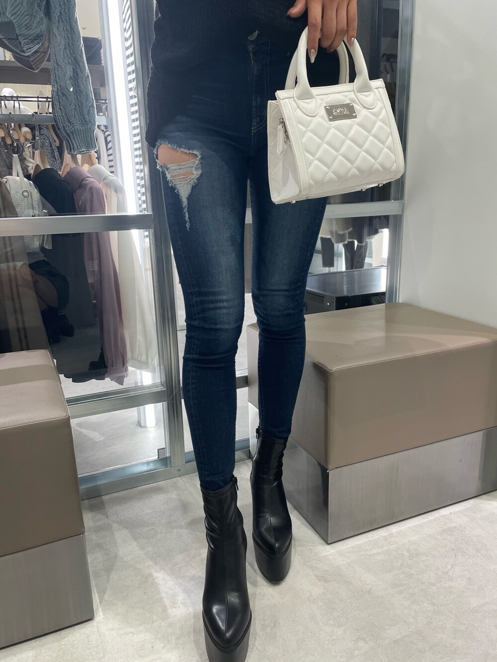 ブラック系のワンピース、ホワイト系のハンドバッグ、ブルー系のデニムパンツを着用したレディースの秋コーディネートの4枚目の写真