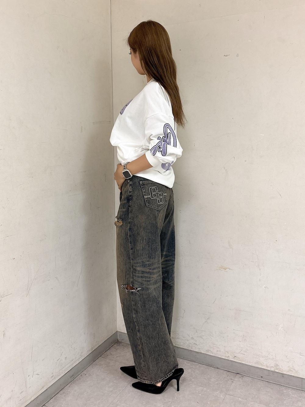 ホワイト系のスウェット、ブルー系のデニムパンツ、ブラック系のパンプスを着用したレディースの秋コーディネートの2枚目の写真