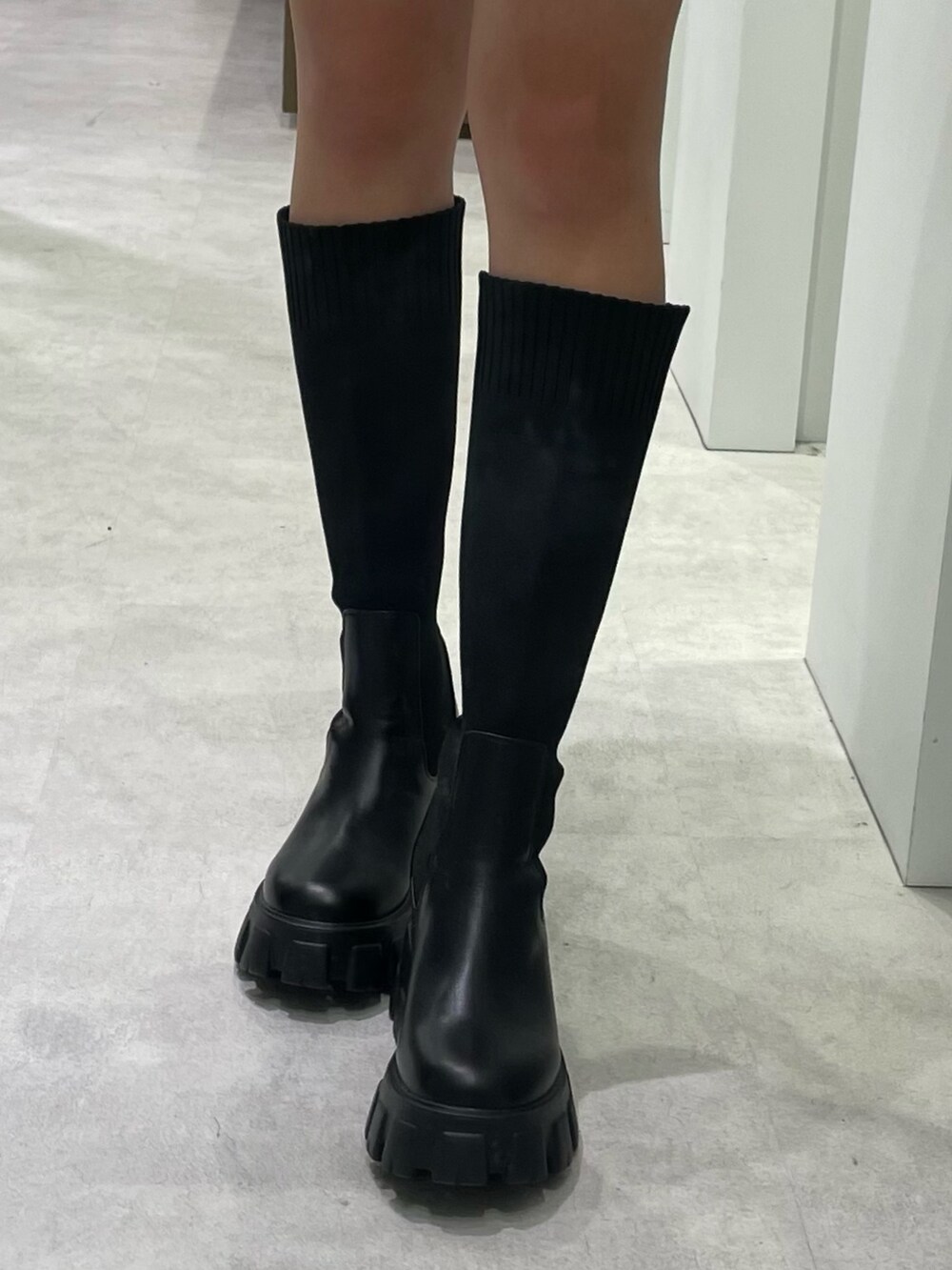 グレー系のニット/セーター、ブラック系のスカート、ブラック系のブーツを着用したレディースの冬コーディネートの5枚目の写真