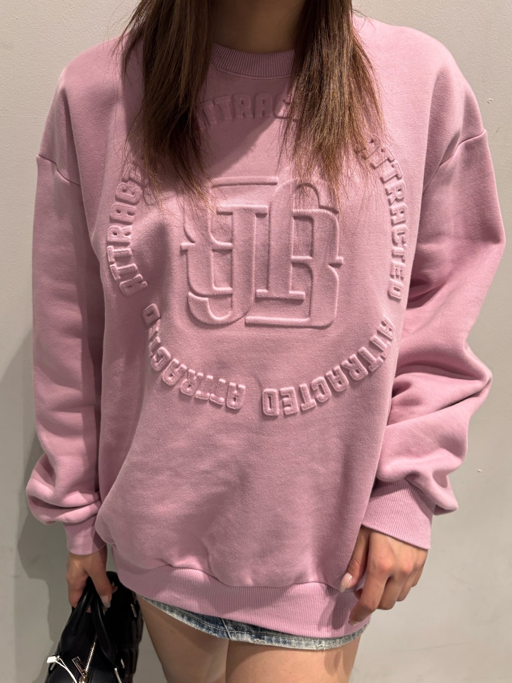 ピンク系のスウェット、ブラック系のハンドバッグ、ブラック系のブーツを着用したレディースの冬コーディネートの4枚目の写真