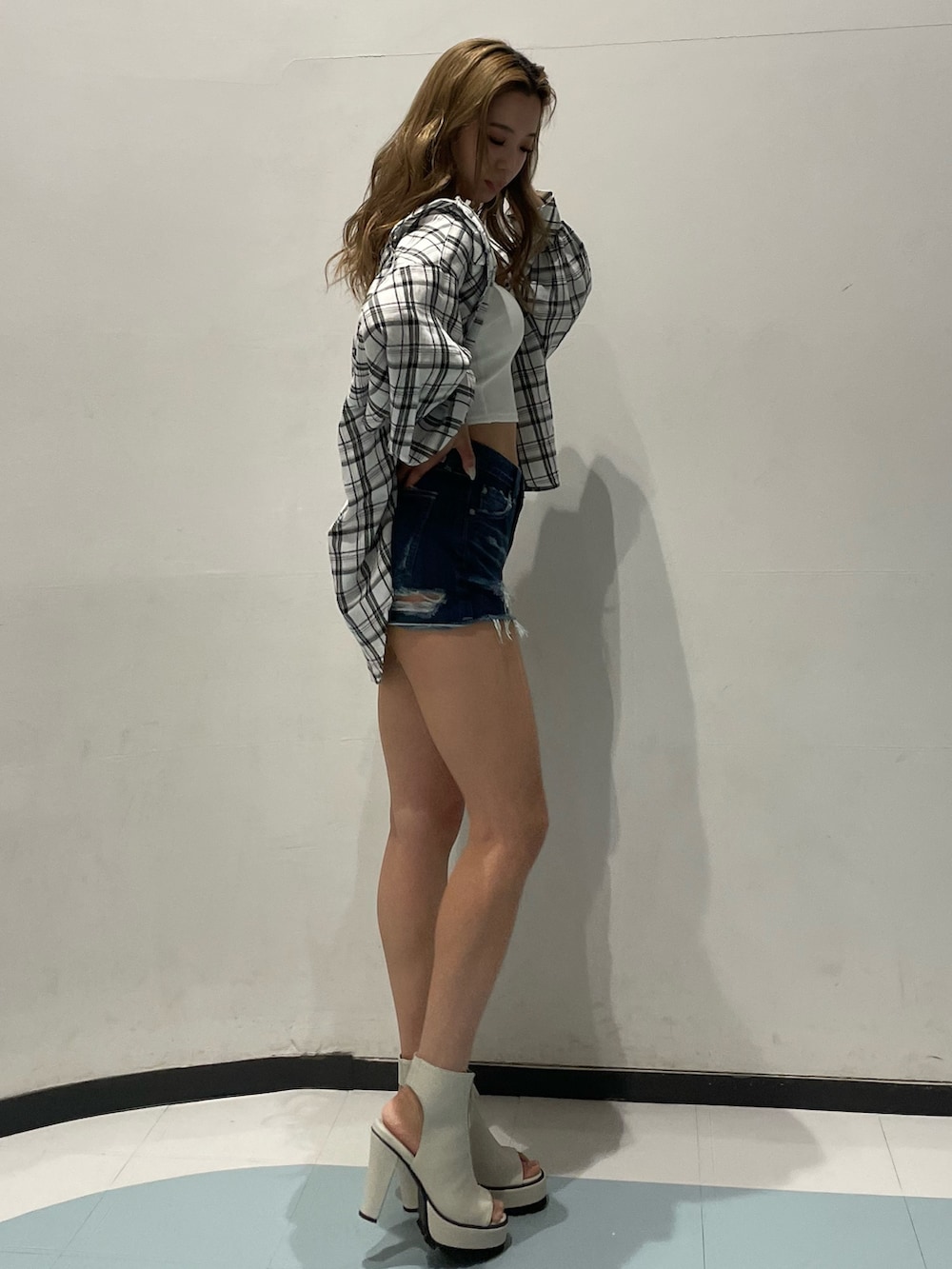 ホワイト系のキャミソール、ブルー系のデニムパンツ、ホワイト系のブーツを着用したレディースの春コーディネートの2枚目の写真