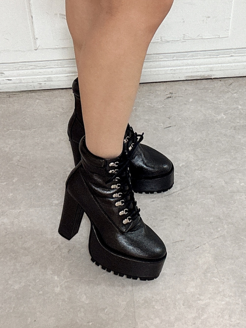 グレー系のニット/セーター、ブラック系のデニムスカート、ブラック系のブーツを着用したレディースの冬コーディネートの5枚目の写真