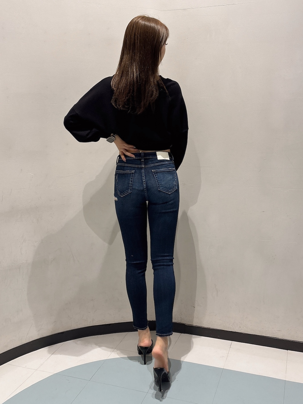 ブルー系のデニムパンツ、ブラック系のニット/セーター、ブラック系のパンプスを着用したレディースの冬コーディネートの3枚目の写真