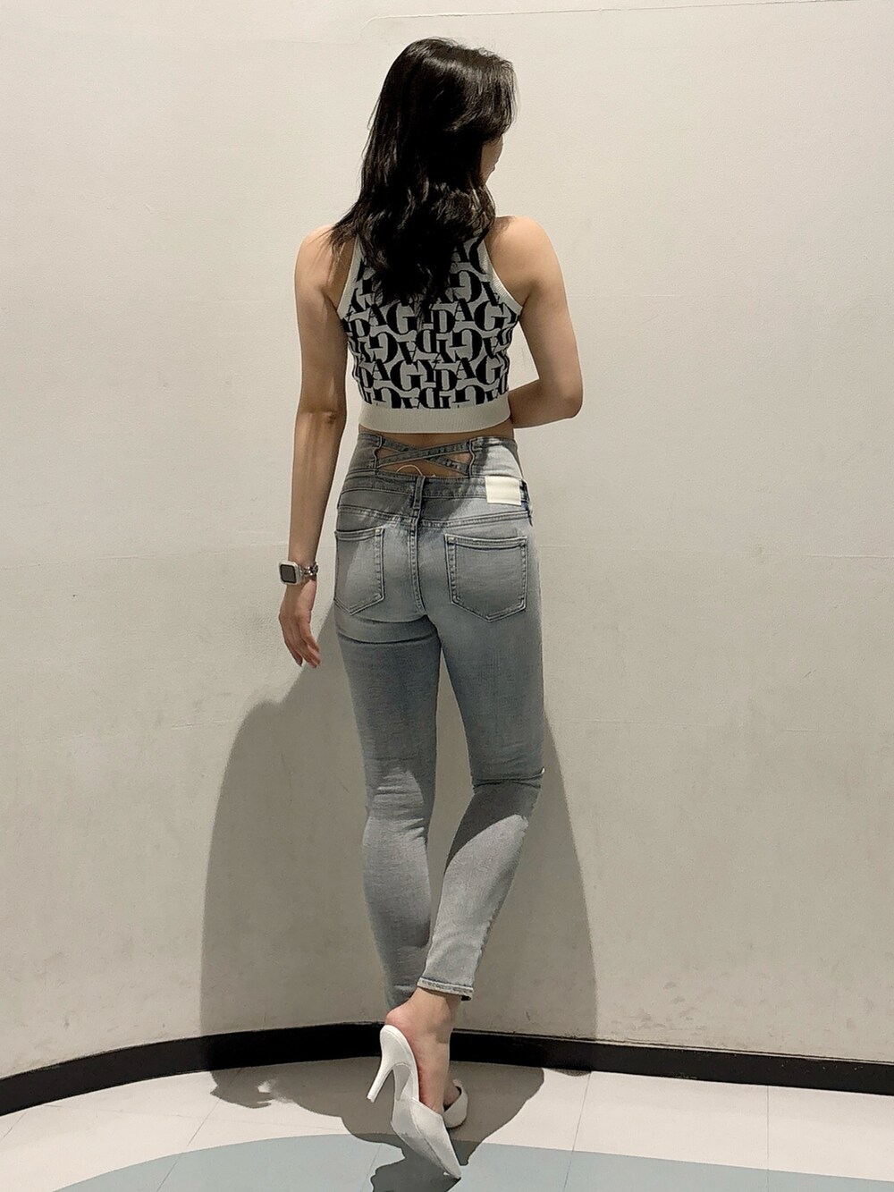 ブルー系のデニムパンツ、ホワイト系のニット/セーター、ホワイト系のパンプスを着用したレディースの春コーディネートの3枚目の写真