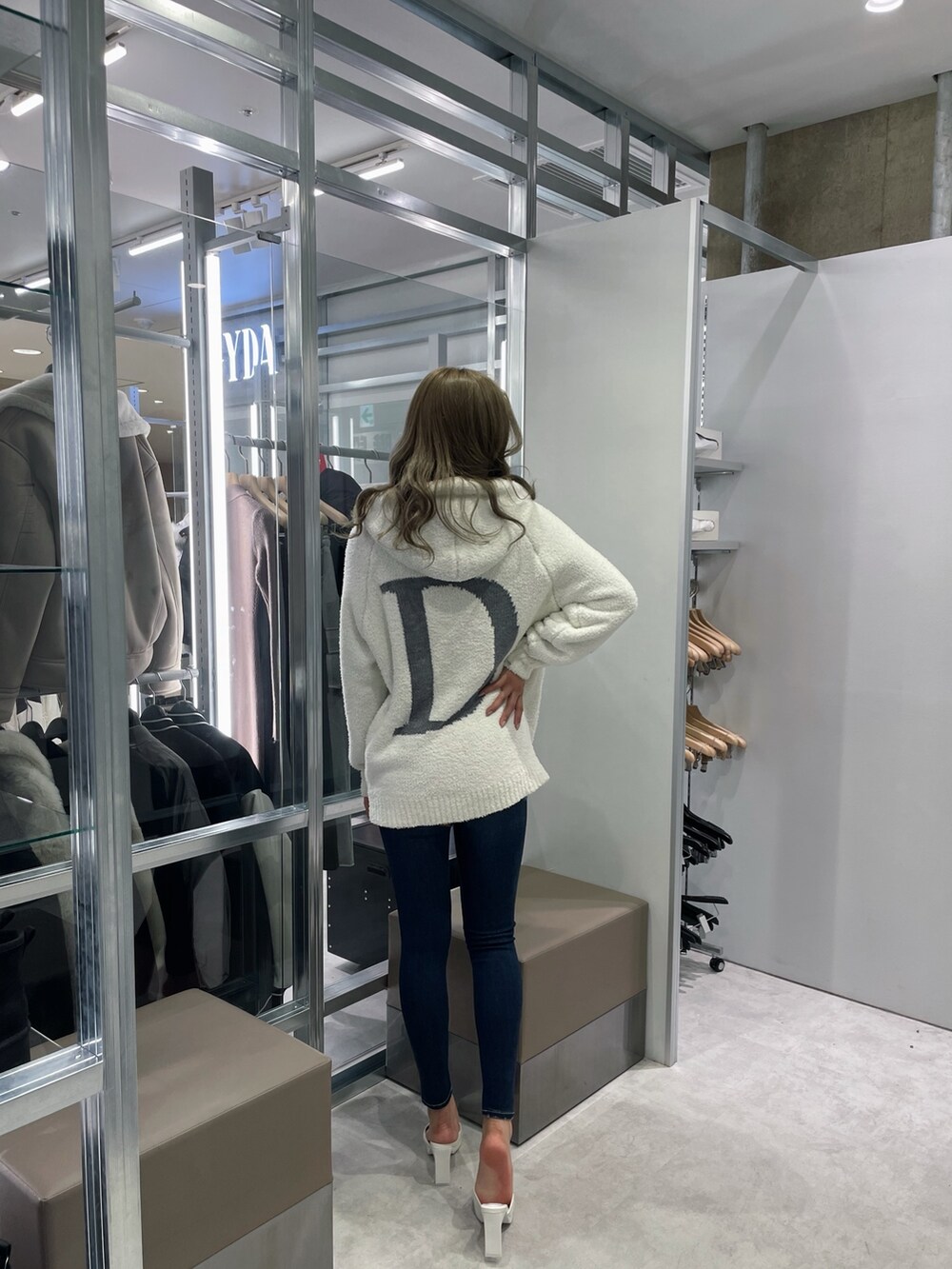 ホワイト系のニット/セーター、ブルー系のデニムパンツ、ホワイト系のパンプスを着用したレディースの冬コーディネートの2枚目の写真