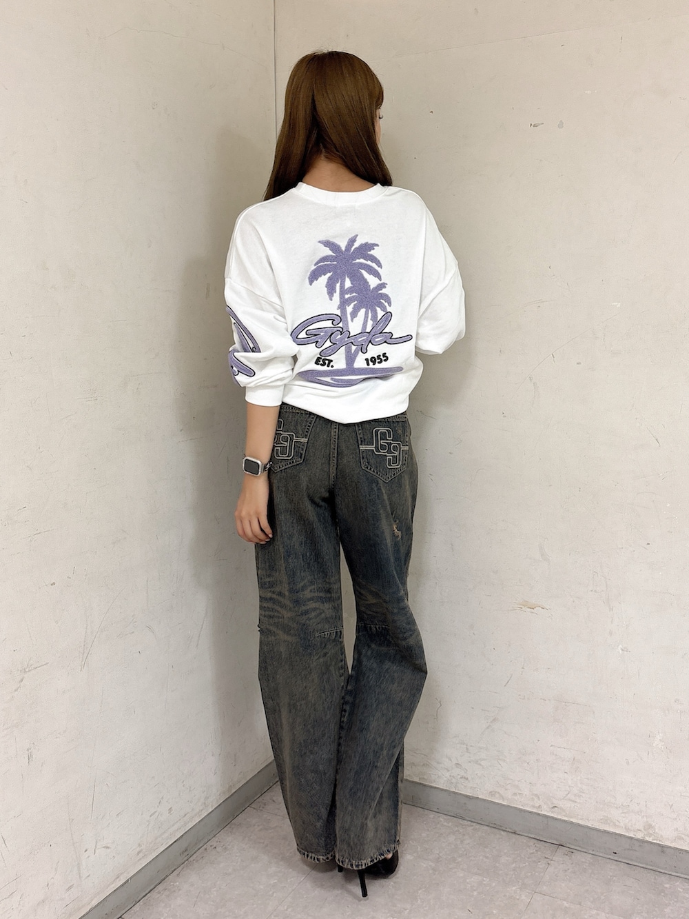 ホワイト系のスウェット、ブルー系のデニムパンツ、ブラック系のパンプスを着用したレディースの秋コーディネートの3枚目の写真