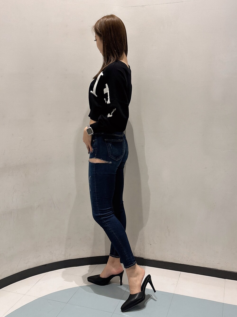 ブルー系のデニムパンツ、ブラック系のニット/セーター、ブラック系のパンプスを着用したレディースの冬コーディネートの2枚目の写真