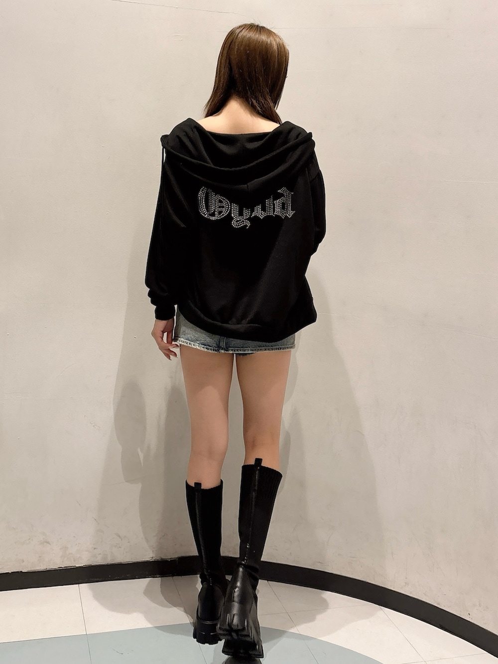 ブルー系のデニムスカート、ブラック系のブーツ、ブラック系のパーカーを着用したレディースの秋コーディネートの3枚目の写真