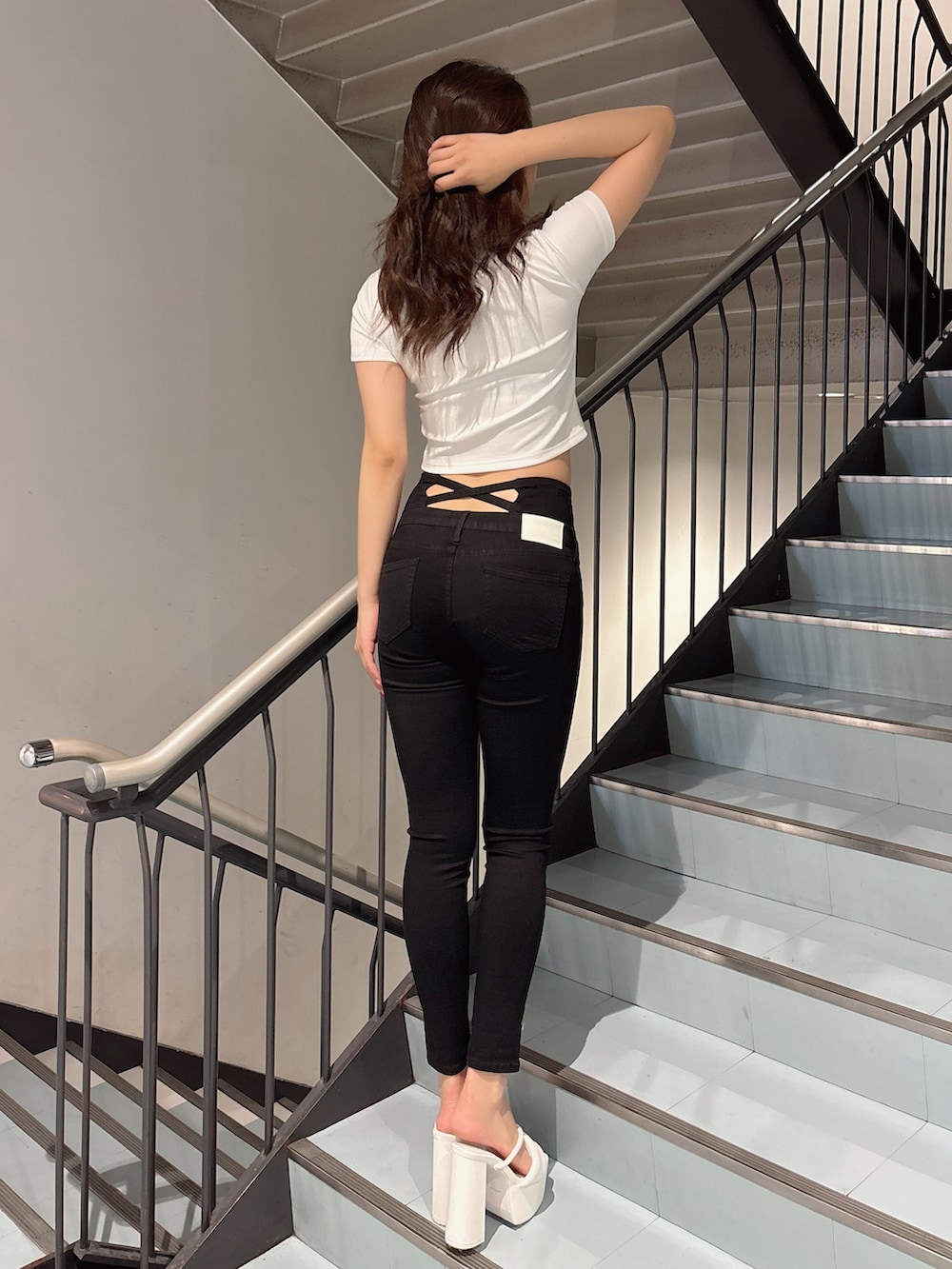 ブラック系のデニムパンツ、ホワイト系のサンダル、ホワイト系のTシャツ/カットソーを着用したレディースの春コーディネートの3枚目の写真