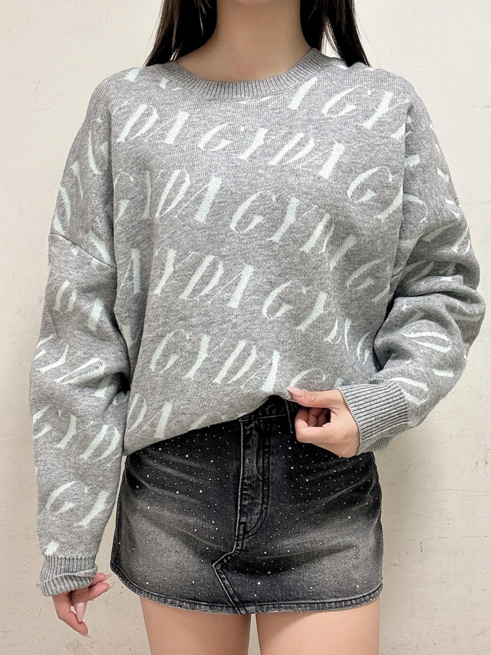 グレー系のニット/セーター、ブラック系のデニムスカート、ブラック系のブーツを着用したレディースの冬コーディネートの4枚目の写真