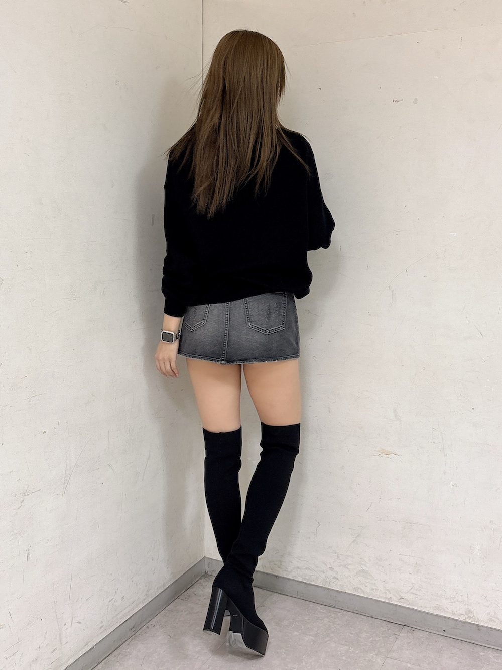 ブラック系のニット/セーター、ブラック系のデニムスカート、ブラック系のブーツを着用したレディースの冬コーディネートの3枚目の写真