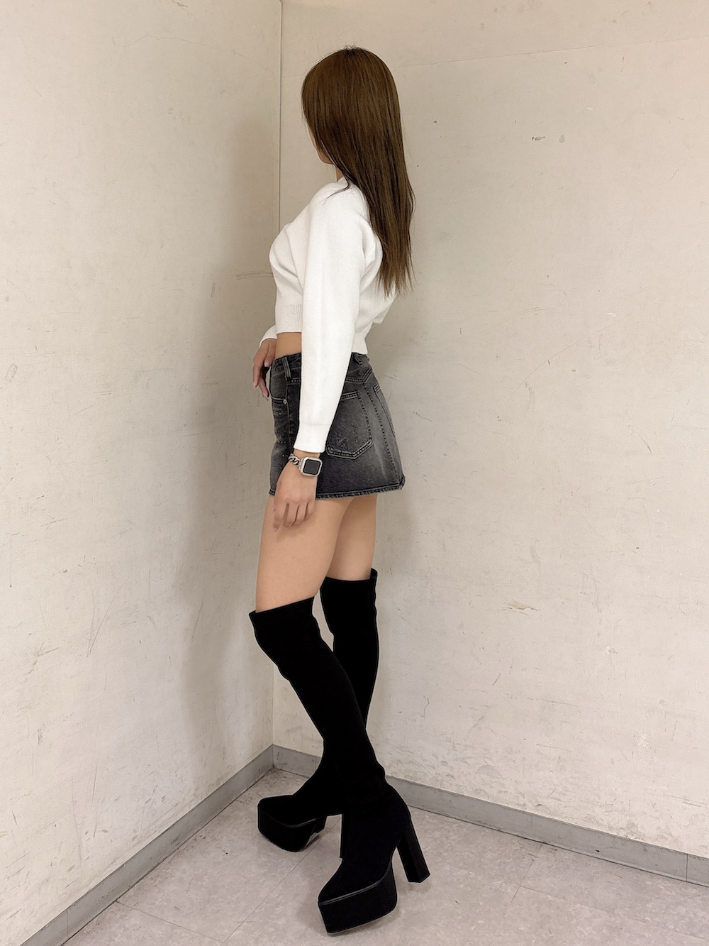 ホワイト系のニット/セーター、ブラック系のデニムスカート、ブラック系のブーツを着用したレディースの冬コーディネートの2枚目の写真
