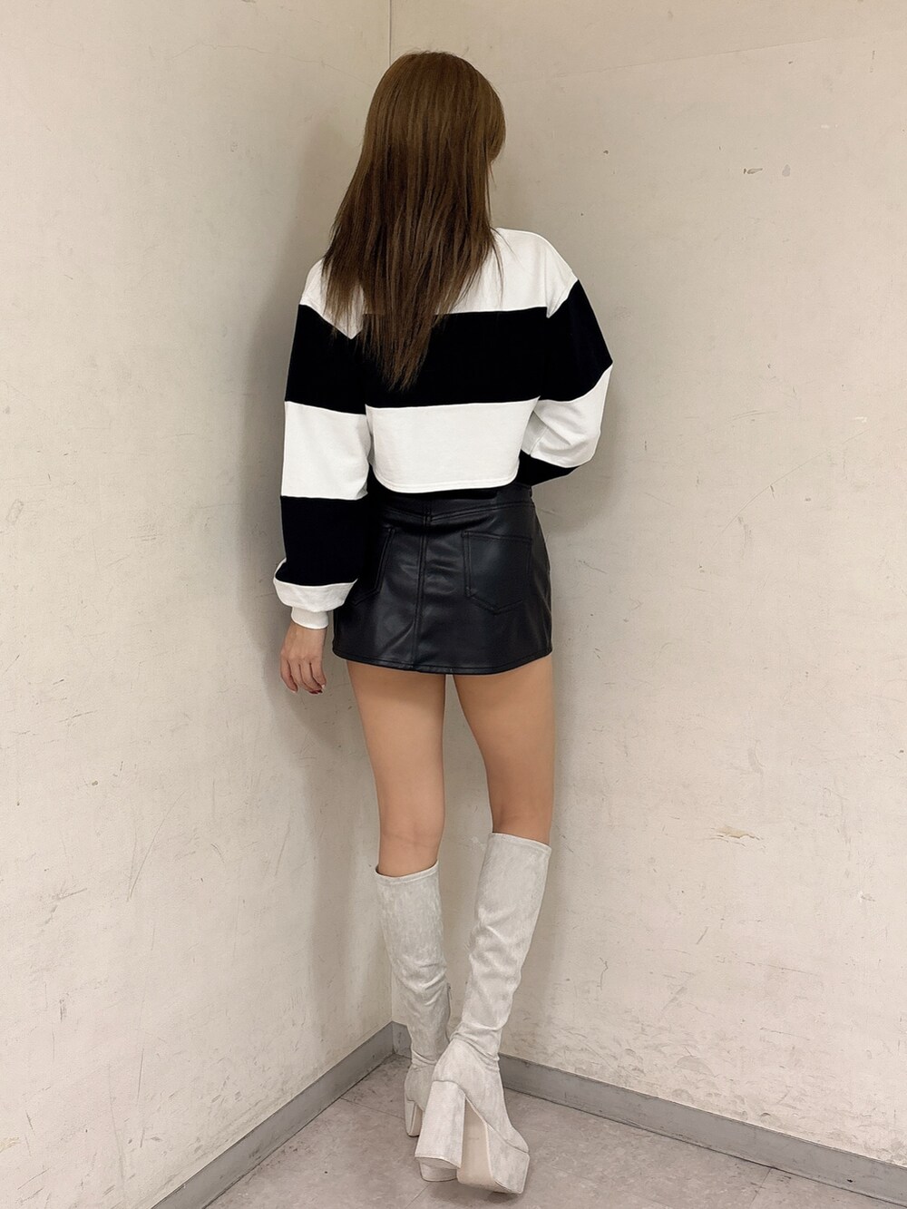 ホワイト系のTシャツ/カットソー、ブラック系のスカート、ホワイト系のブーツを着用したレディースの冬コーディネートの3枚目の写真