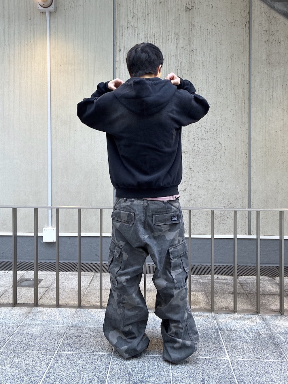 ブラック系のパーカー、レッド系のTシャツ/カットソー、ブラック系のカーゴパンツを着用したメンズの冬コーディネートの3枚目の写真