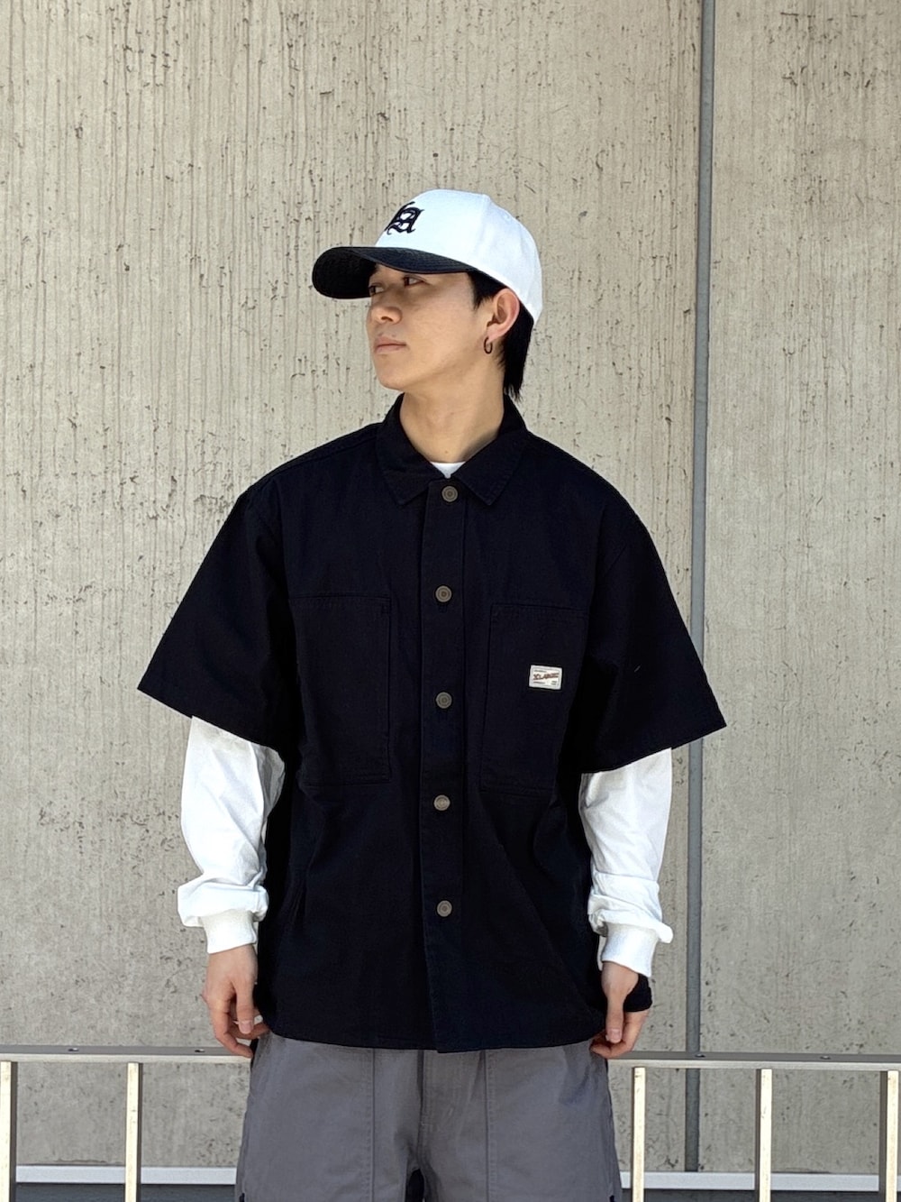 ブラック系のシャツ/ブラウス、グレー系のその他パンツ、ホワイト系のキャップを着用したメンズの春コーディネートの6枚目の写真