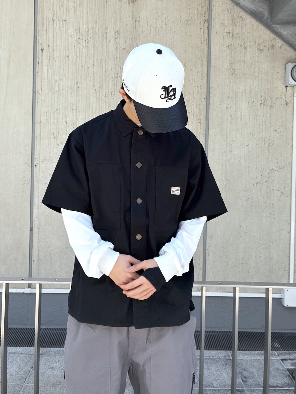 ブラック系のシャツ/ブラウス、グレー系のその他パンツ、ホワイト系のキャップを着用したメンズの春コーディネートの5枚目の写真