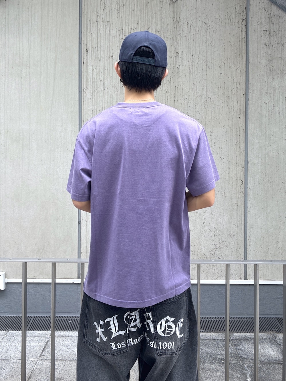パープル系のTシャツ/カットソー、ブラック系のデニムパンツ、ブルー系のキャップを着用したメンズの夏コーディネートの6枚目の写真