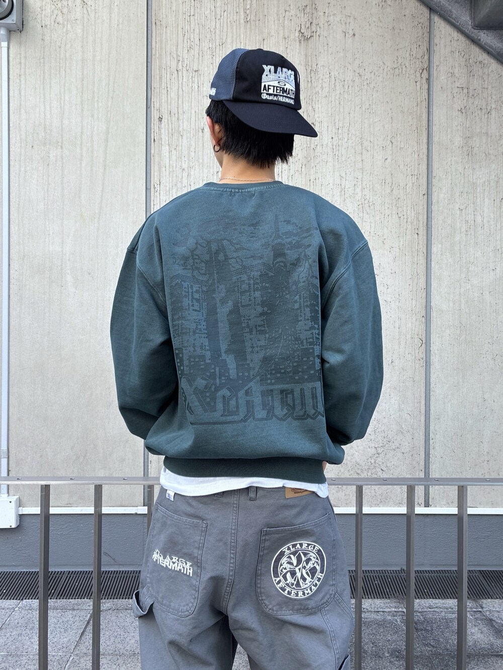 グリーン系のスウェット、グレー系のその他パンツ、ブラック系のキャップを着用したメンズの冬コーディネートの2枚目の写真