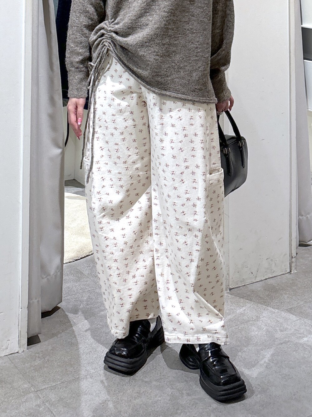 ブラウン系のニット/セーター、ホワイト系のデニムパンツ、ブラック系のハンドバッグを着用したレディースの冬コーディネートの6枚目の写真