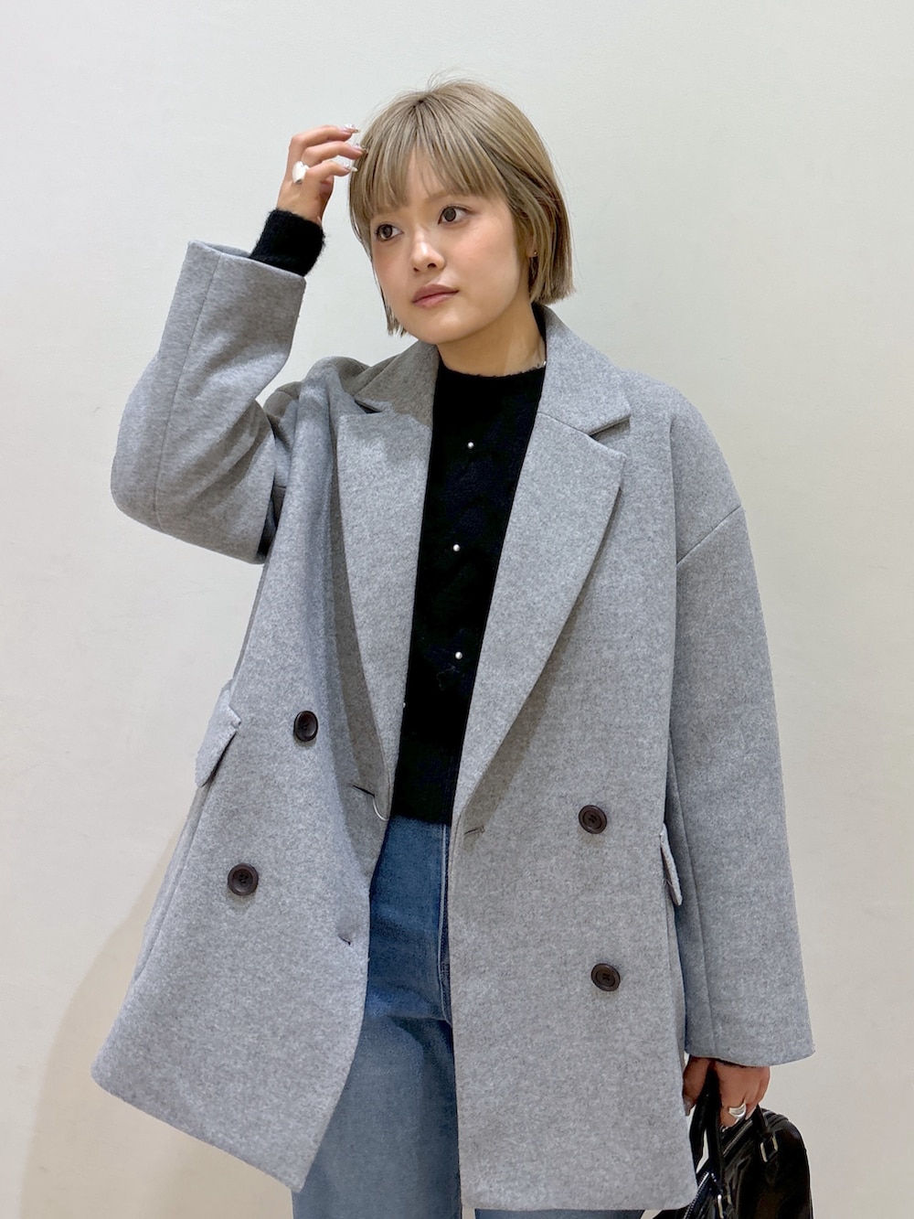 グレー系のピーコート、ブラック系のニット/セーター、ブルー系のデニムパンツを着用したレディースの冬コーディネートの5枚目の写真