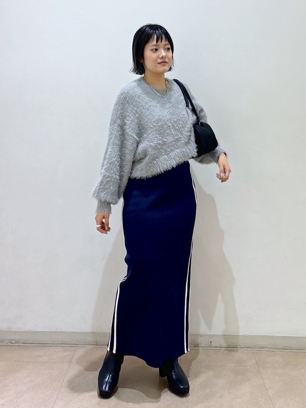 ブルー系のスカート、ブラック系のブーツ、ブラック系のトートバッグを着用したレディースの秋コーディネートの6枚目の写真