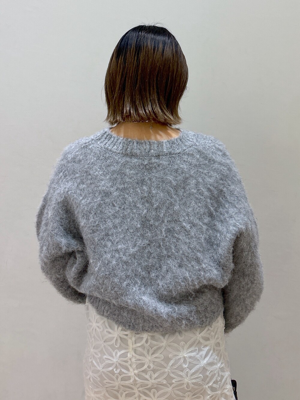 グレー系のニット/セーター、ホワイト系のスカート、ブルー系のショルダーバッグを着用したレディースの冬コーディネートの5枚目の写真