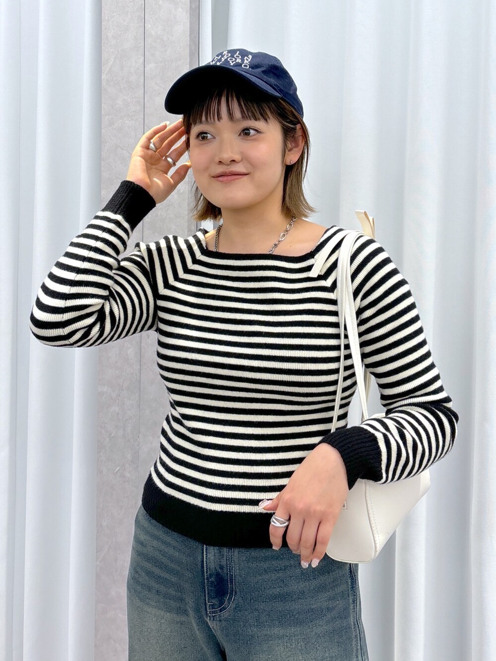 ホワイト系のニット/セーター、ブルー系のデニムパンツ、ホワイト系のショルダーバッグを着用したレディースの冬コーディネートの4枚目の写真