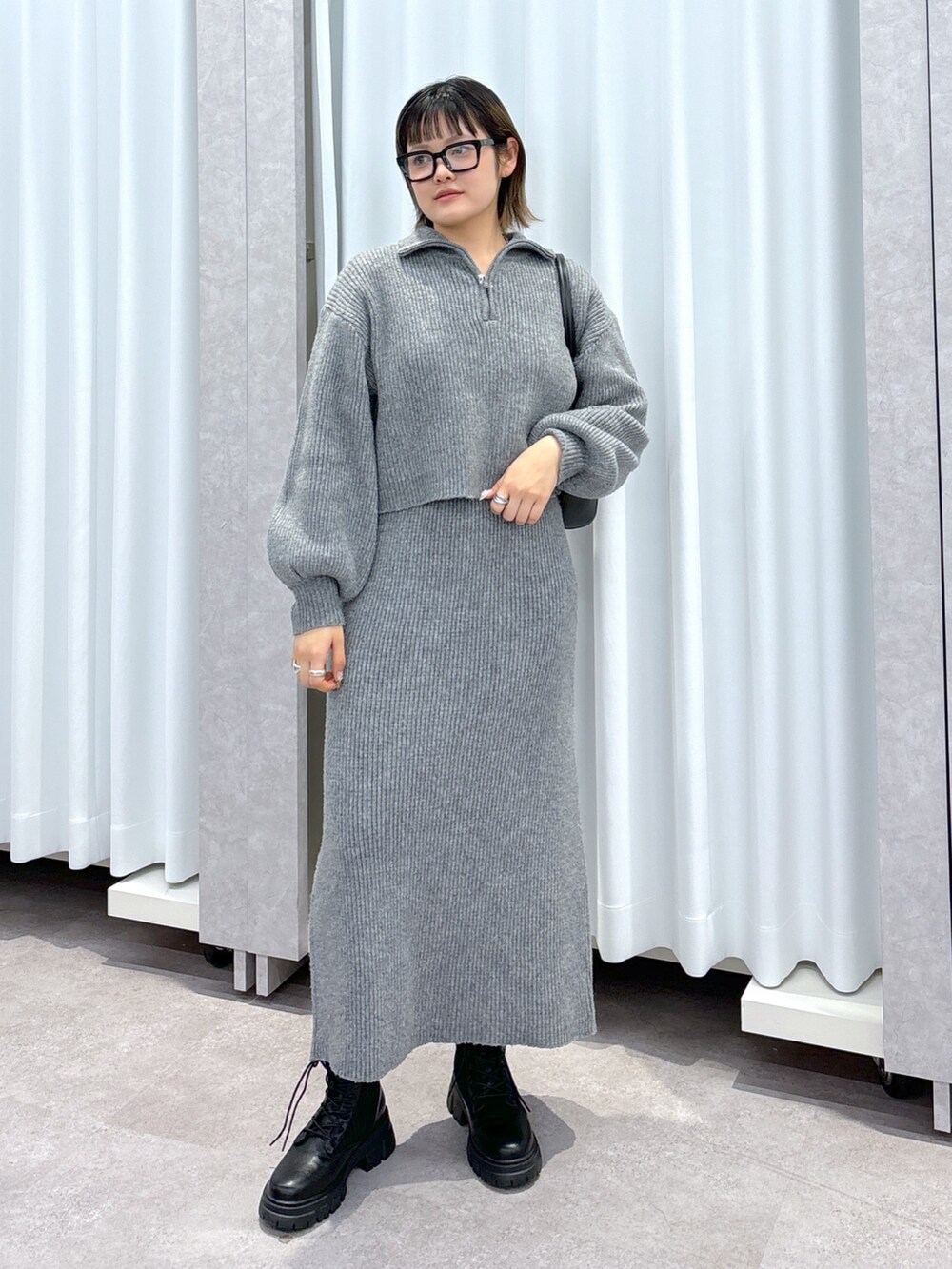 グレー系のワンピース、ブラック系のブーツ、ブラック系のショルダーバッグを着用したレディースの冬コーディネートの6枚目の写真