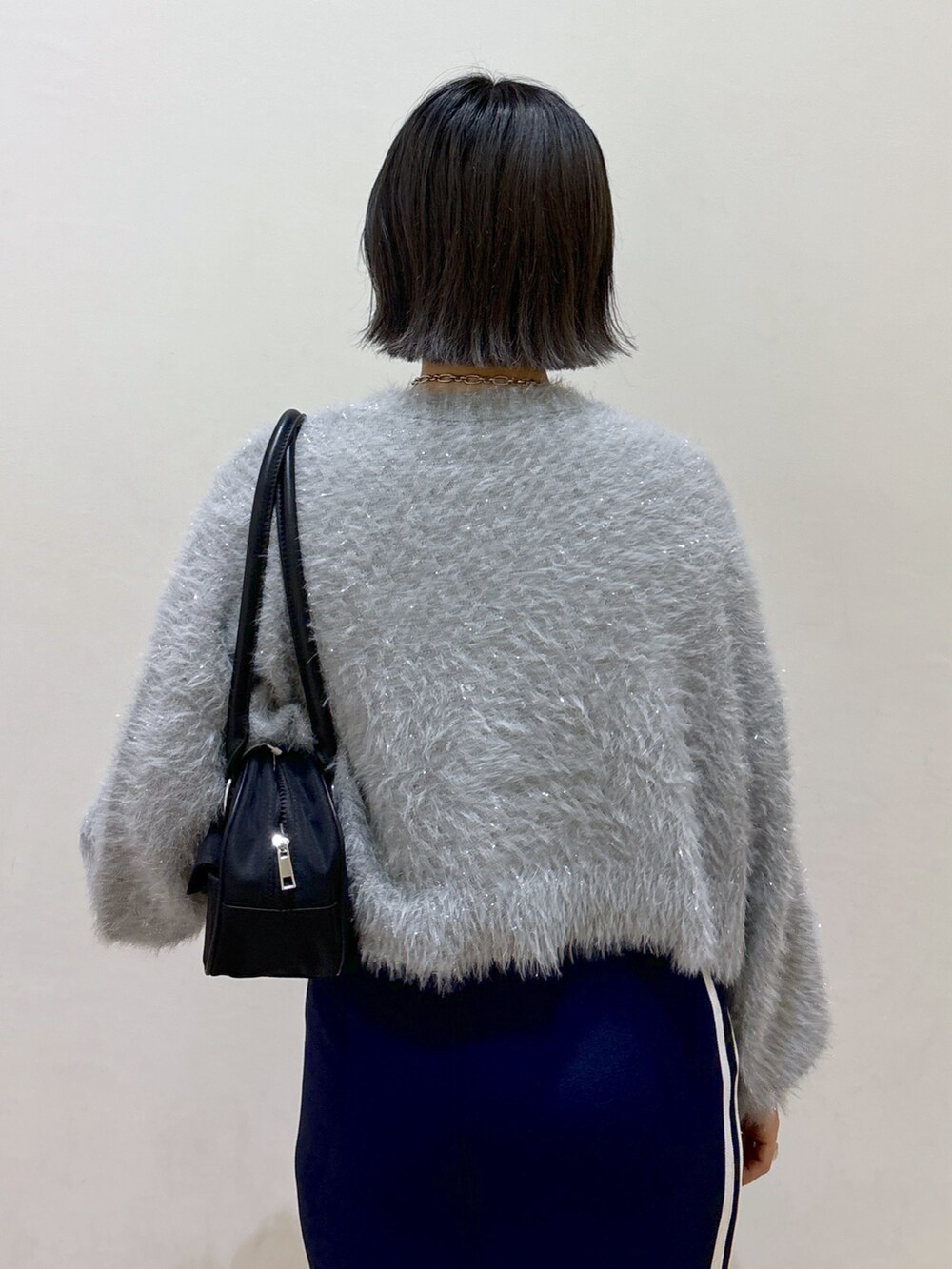 ブルー系のスカート、ブラック系のブーツ、ブラック系のトートバッグを着用したレディースの秋コーディネートの5枚目の写真