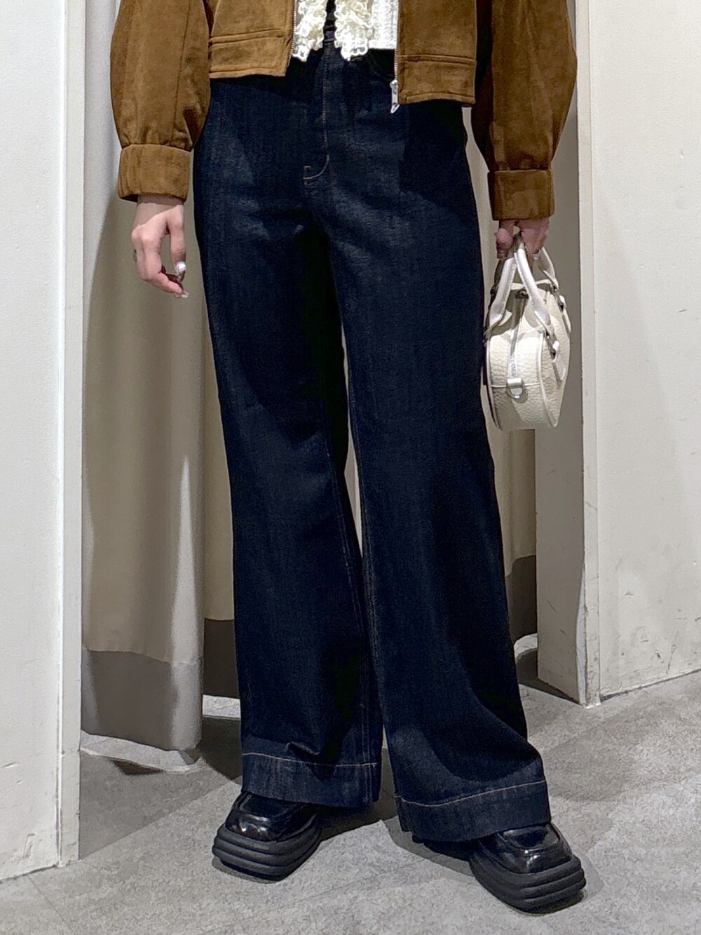 ブラウン系のブルゾン、ホワイト系のニット/セーター、ブルー系のデニムパンツを着用したレディースの秋コーディネートの7枚目の写真