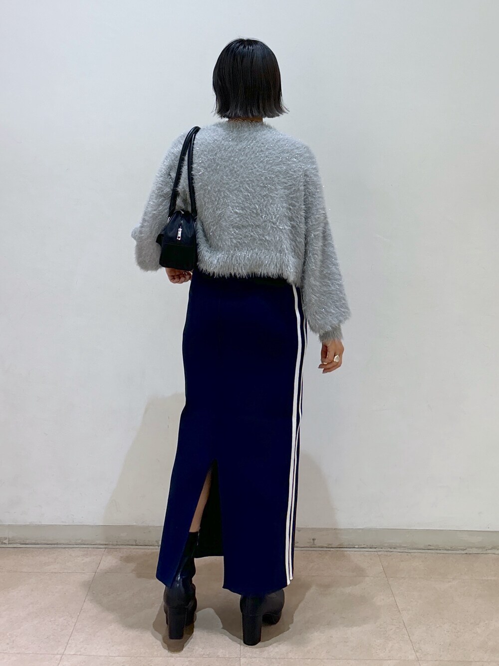 ブルー系のスカート、ブラック系のブーツ、ブラック系のトートバッグを着用したレディースの秋コーディネートの3枚目の写真