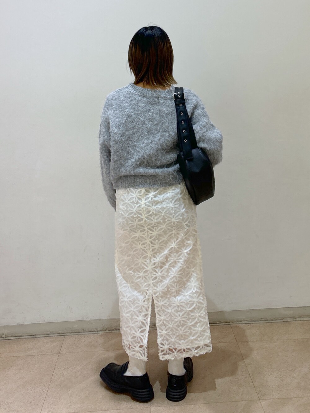 グレー系のニット/セーター、ホワイト系のスカート、ブルー系のショルダーバッグを着用したレディースの冬コーディネートの3枚目の写真