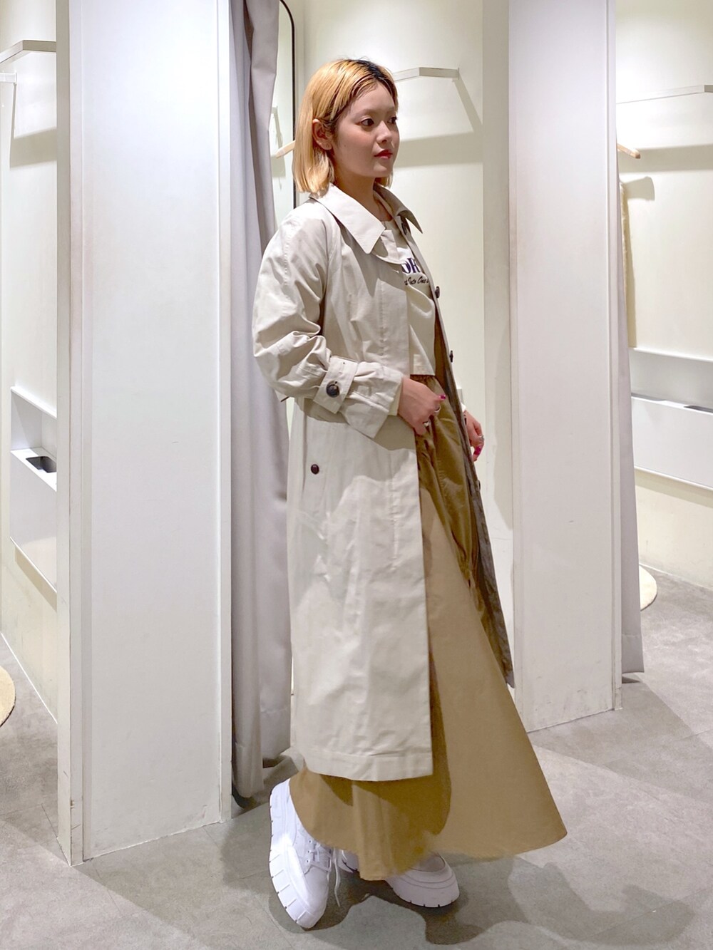 ベージュ系のトレンチコート、ベージュ系のスカート、ブラウン系のショルダーバッグを着用したレディースの冬コーディネートの5枚目の写真