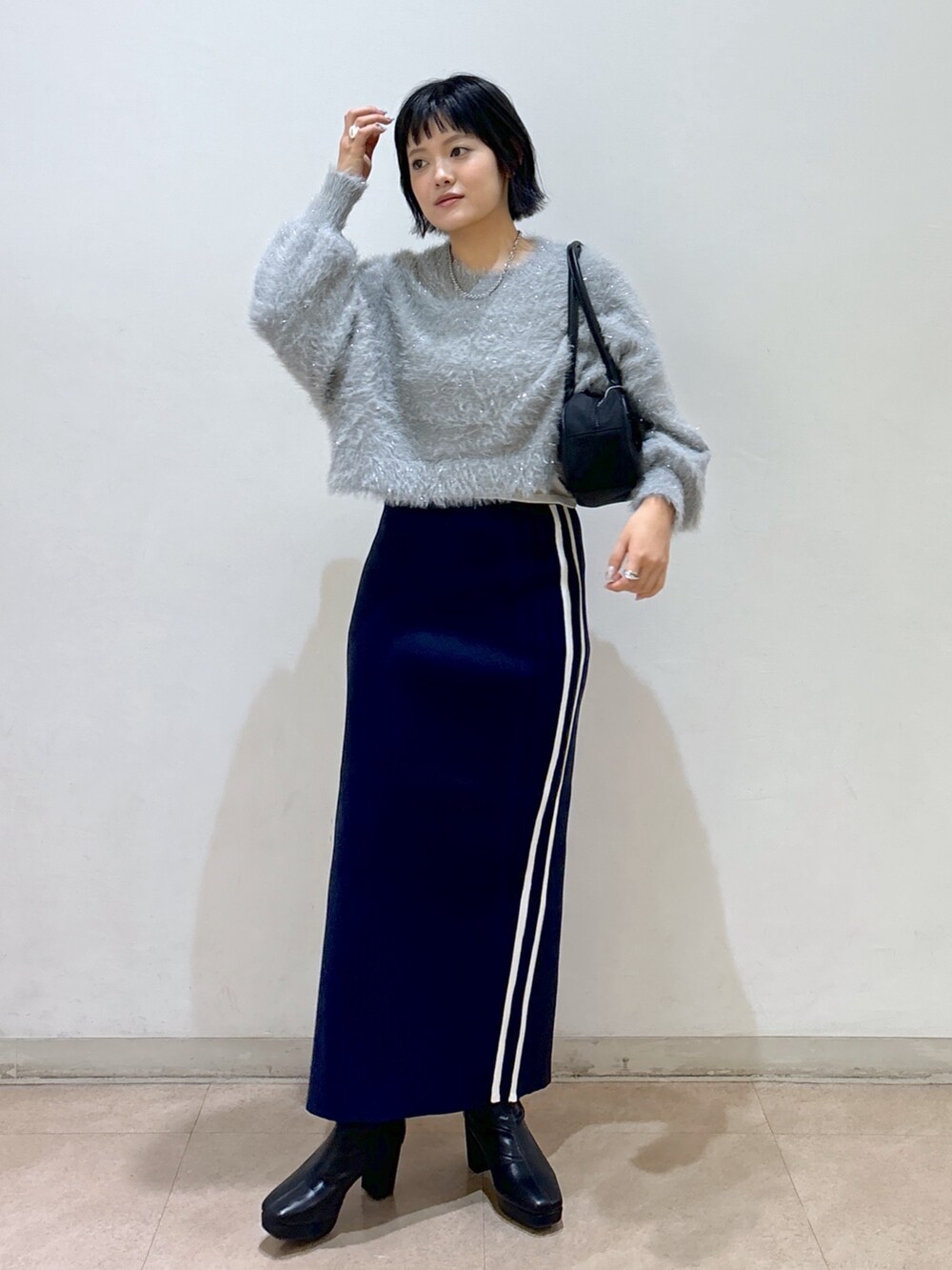 ブルー系のスカート、ブラック系のブーツ、ブラック系のトートバッグを着用したレディースの秋コーディネートの2枚目の写真